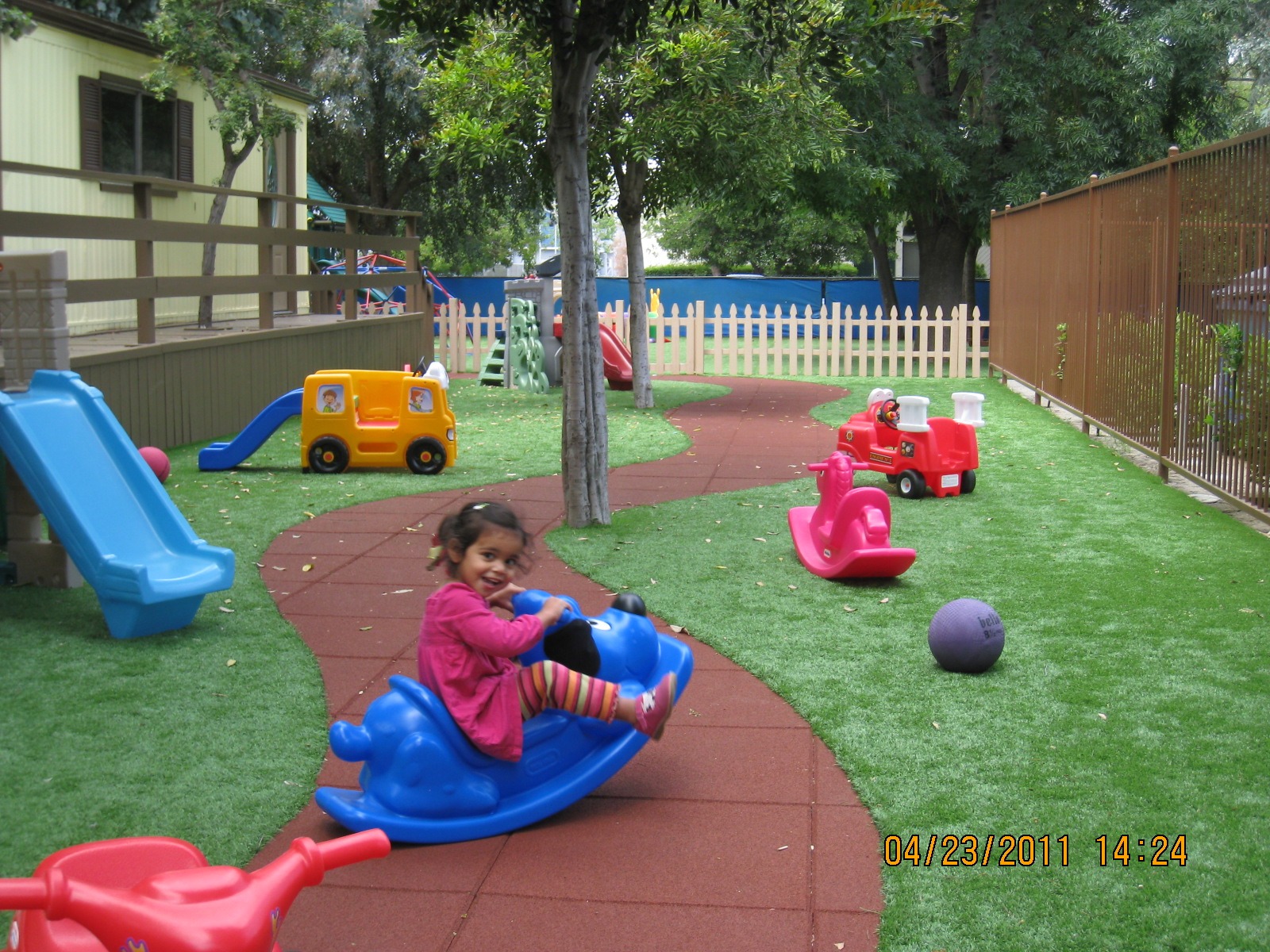 A small girl joyfully riding a colorful toy car, showcasing her playful spirit and imagination.