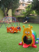 A vibrant playground featuring slides and swings, set in a spacious yard filled with green grass and colorful equipment.
