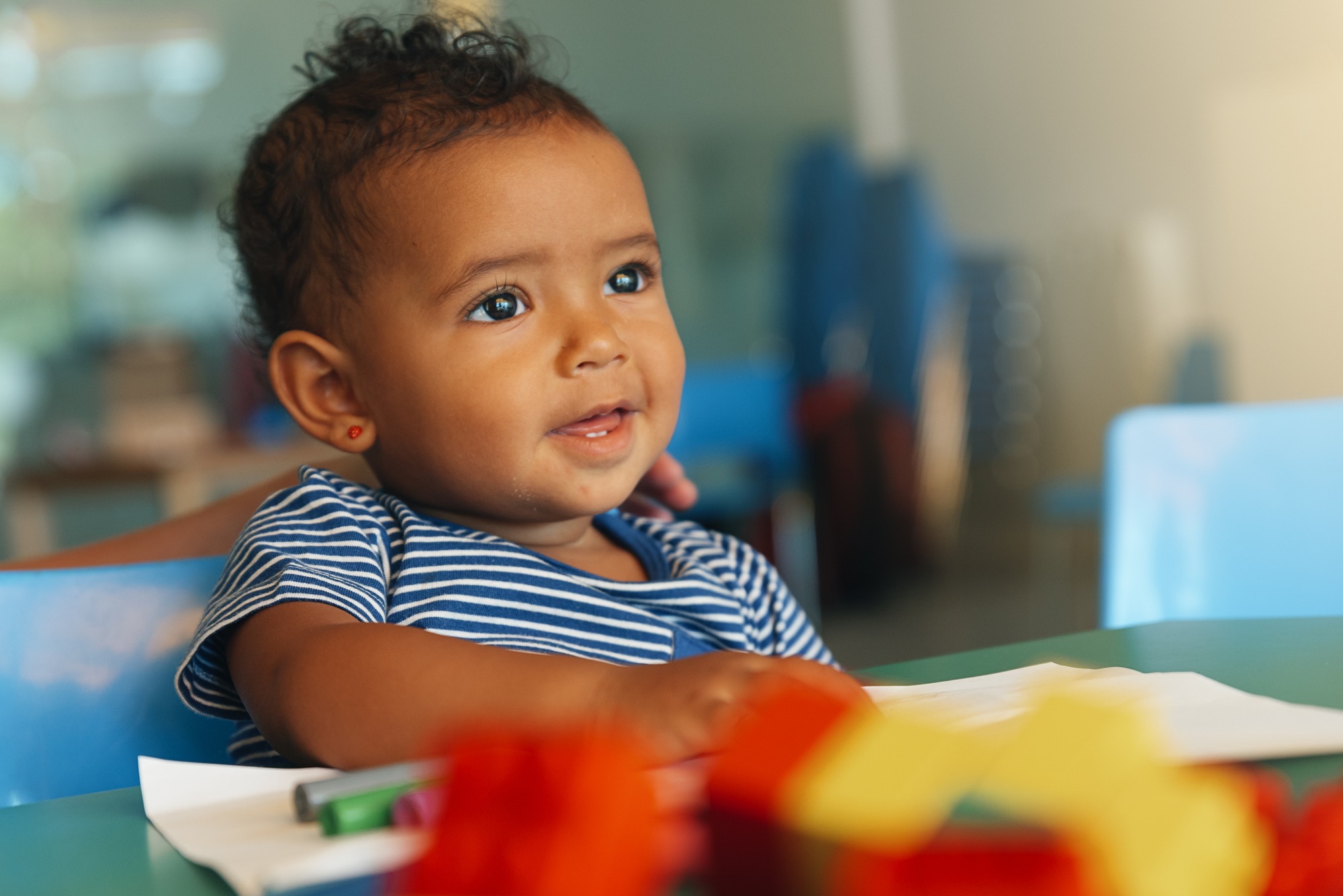 Happy baby playing with toy blocks in the kindergarten.