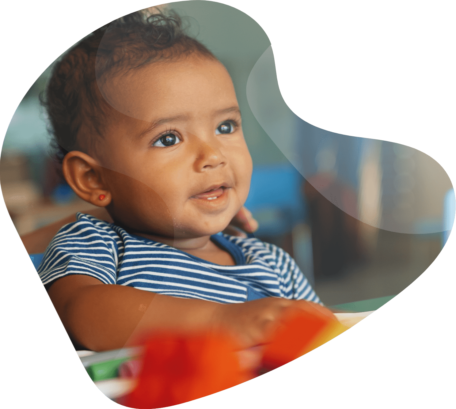 Happy baby playing with toy blocks in the kindergarten.